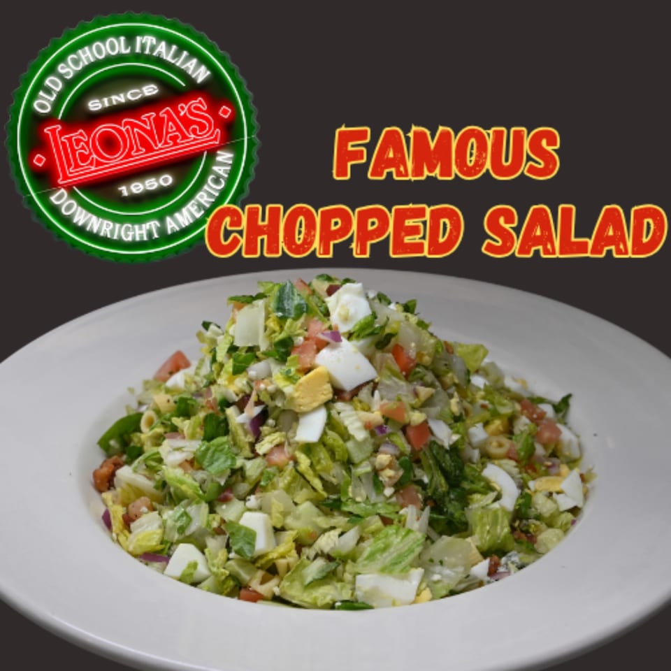 Leona's Pizzeria's famous chopped salad with lettuce, tomatoes, eggs, and olives in a white bowl.